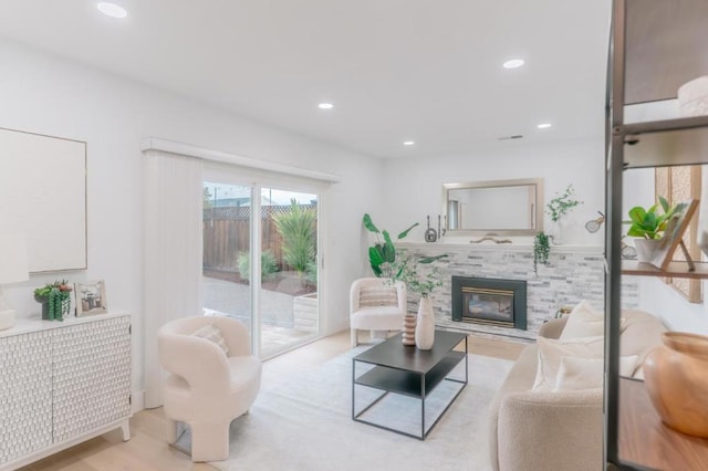 living room featuring a tiled fireplace and light wood-type flooring