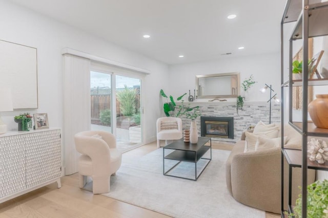 living room featuring a tiled fireplace and light wood-type flooring