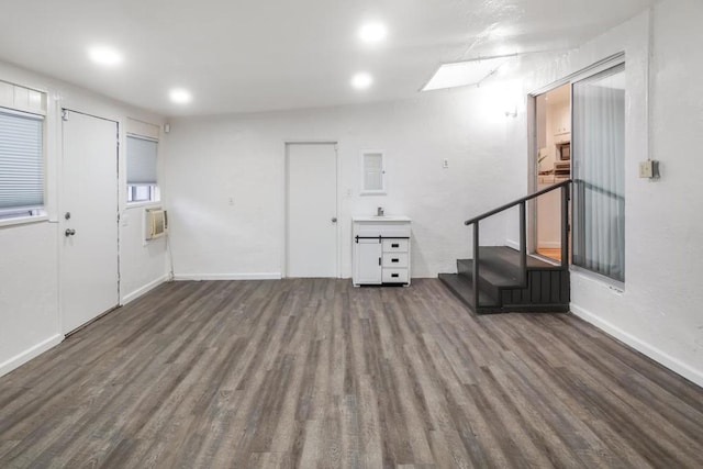 interior space with dark wood-type flooring, a wall mounted AC, a skylight, and sink