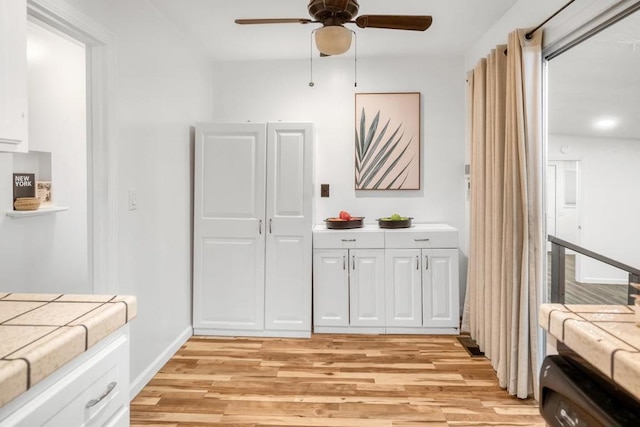 kitchen featuring white cabinetry, ceiling fan, tile counters, and light hardwood / wood-style floors