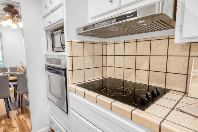 kitchen featuring extractor fan, white cabinetry, black appliances, ceiling fan, and backsplash