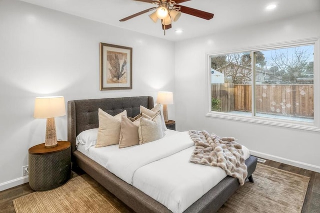 bedroom featuring multiple windows, dark hardwood / wood-style floors, and ceiling fan