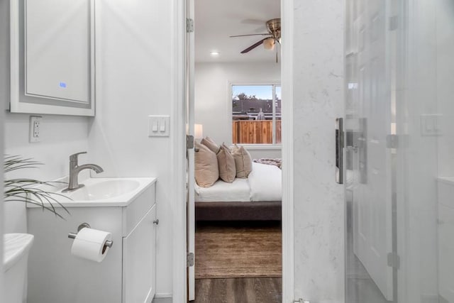 bathroom featuring hardwood / wood-style floors, vanity, walk in shower, ceiling fan, and toilet