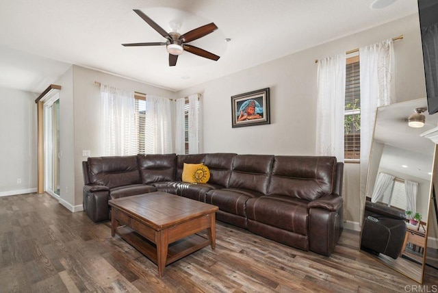 living area with dark wood-type flooring, baseboards, and a ceiling fan