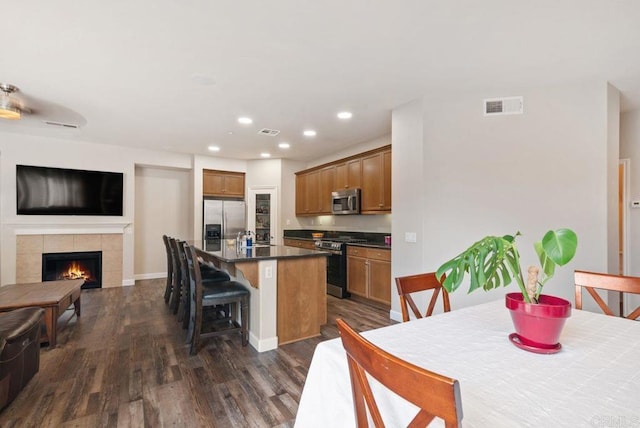 kitchen featuring stainless steel appliances, dark countertops, visible vents, a kitchen island, and a kitchen breakfast bar