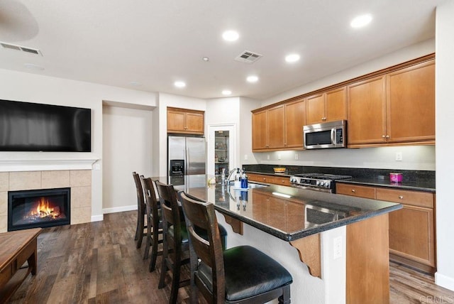 kitchen featuring open floor plan, appliances with stainless steel finishes, a sink, and a center island with sink