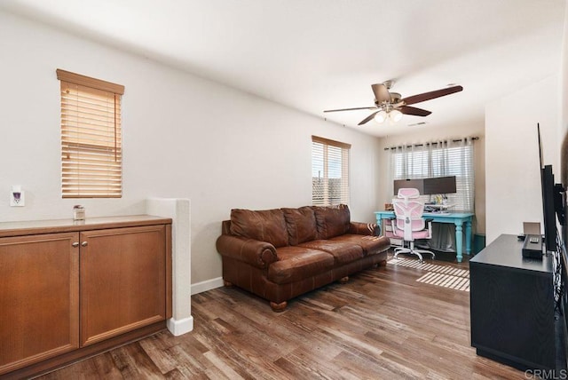 living area featuring wood finished floors, a ceiling fan, and baseboards