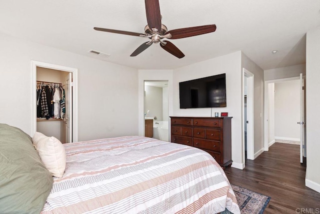 bedroom featuring dark wood-style floors, a closet, visible vents, a spacious closet, and baseboards