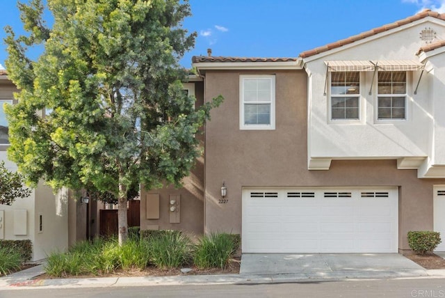 townhome / multi-family property featuring driveway, a tiled roof, and stucco siding