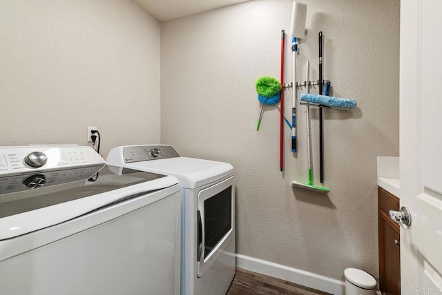 laundry area featuring cabinet space, dark wood-style floors, baseboards, and washing machine and clothes dryer