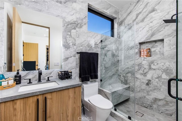 bathroom with vanity, a shower with door, tile walls, and toilet