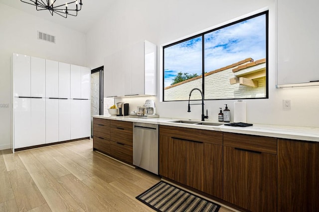 kitchen featuring dark brown cabinetry, sink, white cabinetry, light wood-type flooring, and stainless steel dishwasher