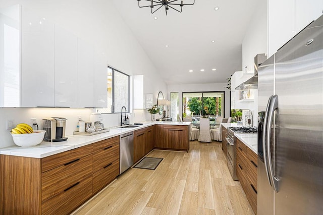 kitchen featuring appliances with stainless steel finishes, sink, white cabinets, and light wood-type flooring