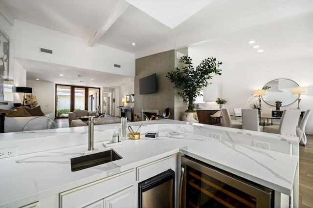 kitchen with wine cooler, light hardwood / wood-style floors, light stone counters, and white cabinets