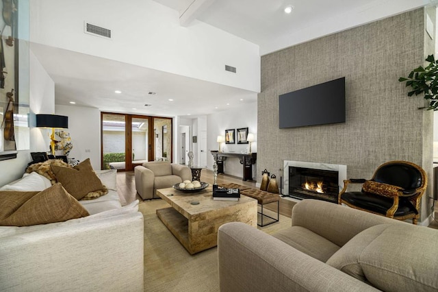 living room with beamed ceiling, a large fireplace, and a high ceiling