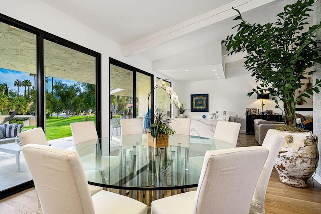 dining room featuring vaulted ceiling with beams and light hardwood / wood-style flooring