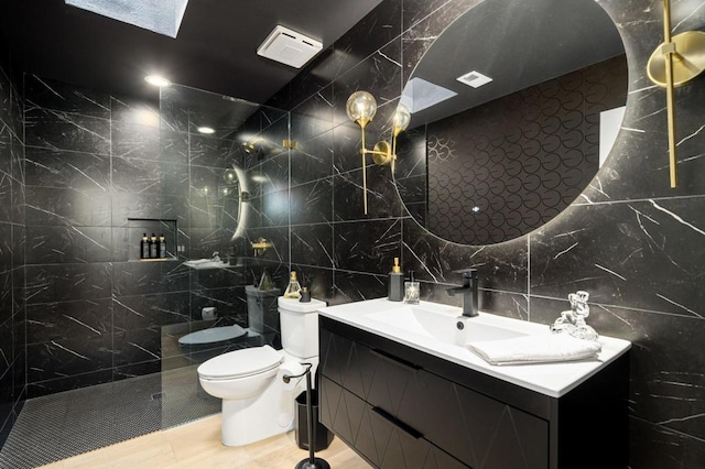 bathroom with vanity, toilet, tile walls, and a tile shower