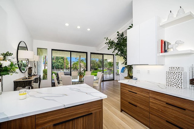 kitchen featuring light stone counters, light wood-type flooring, and white cabinets