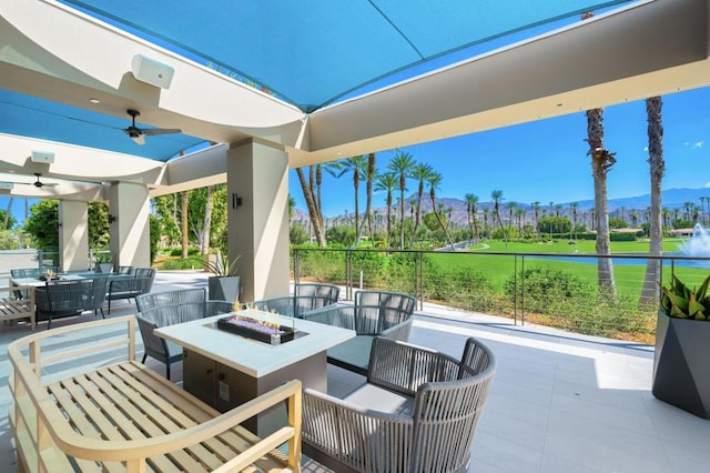 view of patio featuring a mountain view, ceiling fan, and a fire pit