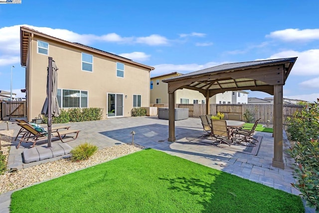 back of property featuring a gazebo, a patio area, and a lawn