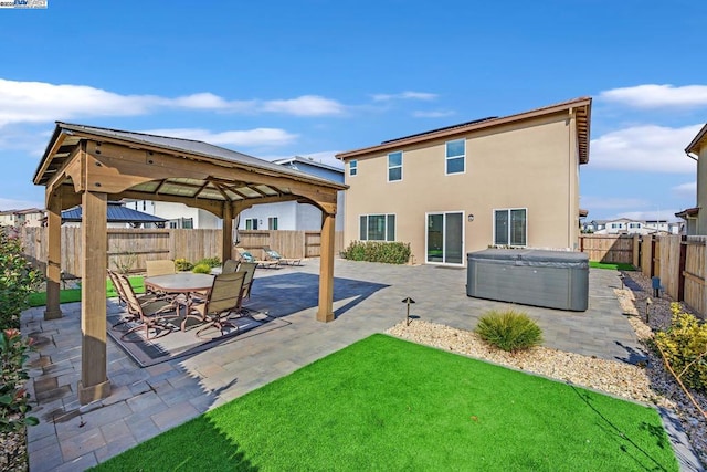 back of property with a gazebo, a yard, a hot tub, and a patio area