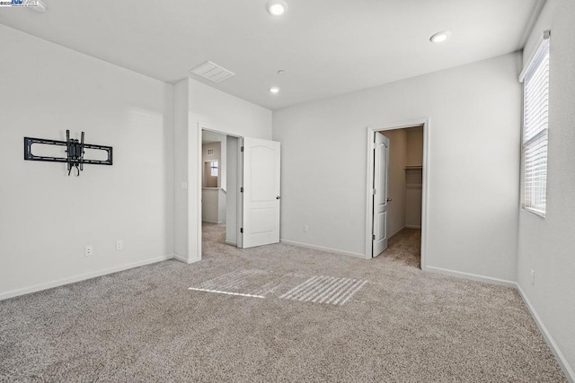 unfurnished bedroom featuring a spacious closet and light colored carpet