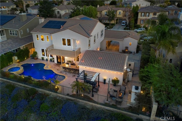 rear view of property with a fenced backyard, a balcony, a tiled roof, a residential view, and a patio area