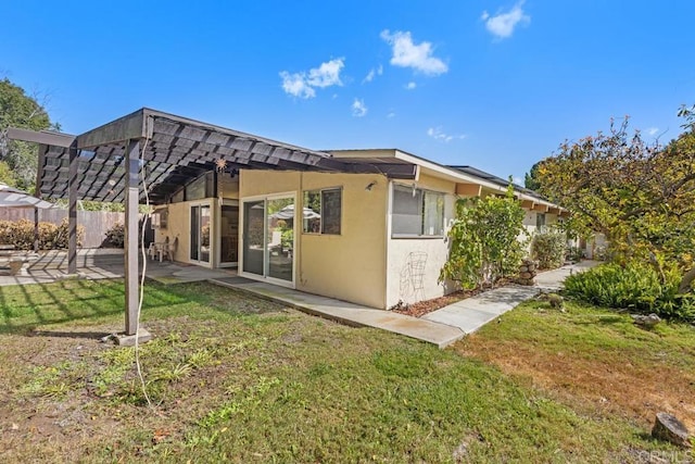 rear view of property featuring a yard, a patio area, and stucco siding