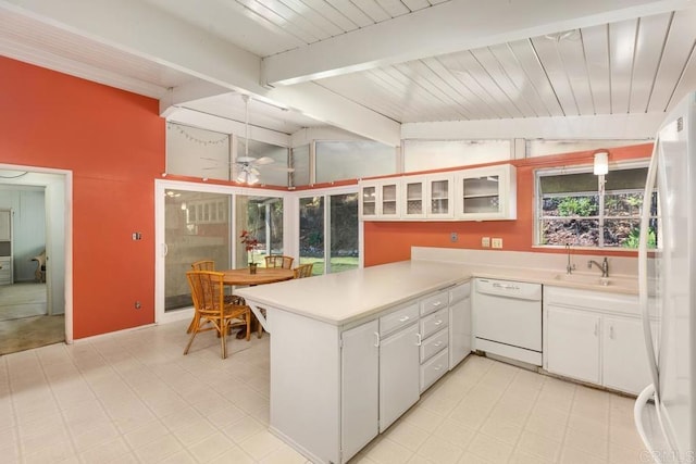 kitchen featuring vaulted ceiling with beams, a peninsula, white appliances, light countertops, and light floors