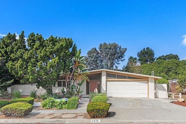 view of front of house featuring driveway, an attached garage, and fence