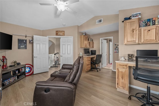 living room featuring vaulted ceiling, built in desk, ceiling fan, light hardwood / wood-style floors, and a barn door