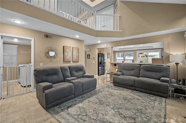 tiled living room featuring washer and dryer and a high ceiling