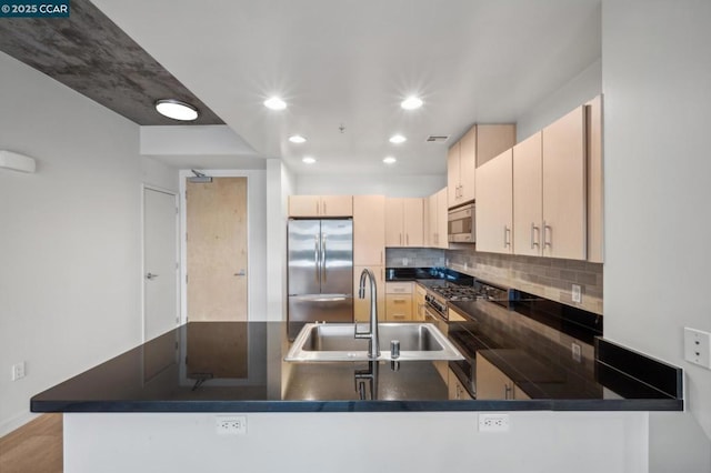 kitchen featuring tasteful backsplash, sink, kitchen peninsula, and appliances with stainless steel finishes