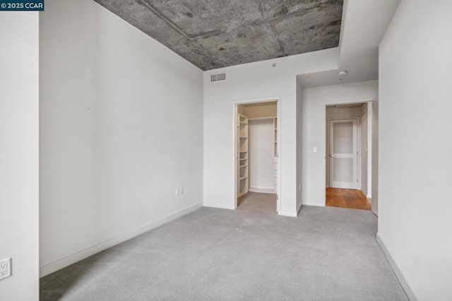 unfurnished bedroom with light colored carpet, a spacious closet, and a closet