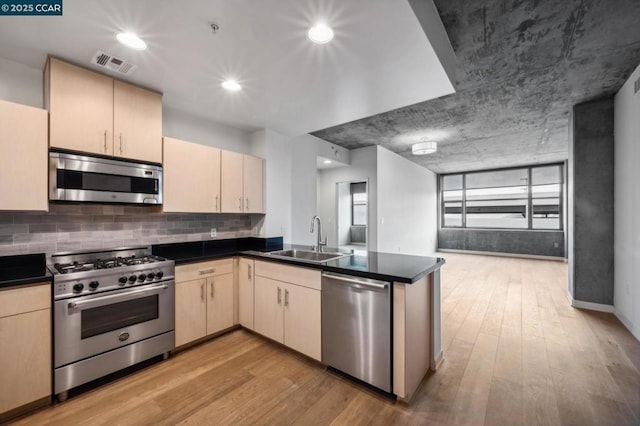 kitchen with tasteful backsplash, sink, light hardwood / wood-style floors, kitchen peninsula, and stainless steel appliances