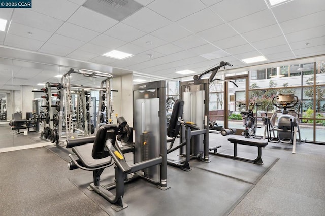 workout area with a wall of windows and a drop ceiling