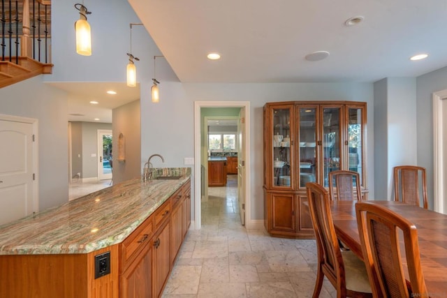 kitchen with hanging light fixtures, sink, and light stone counters