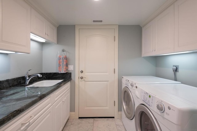 clothes washing area featuring sink, washer and clothes dryer, and cabinets