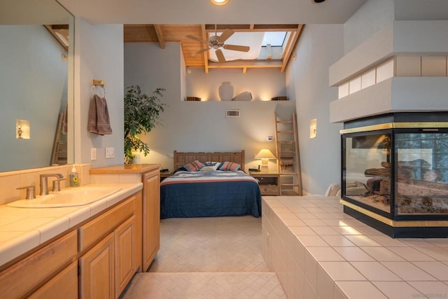 bedroom featuring sink, beam ceiling, a skylight, a high ceiling, and access to outside