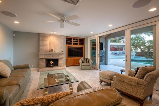 living room featuring ceiling fan, a fireplace, and built in features