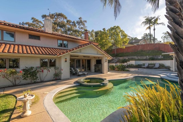 back of property featuring a patio and a pool with hot tub