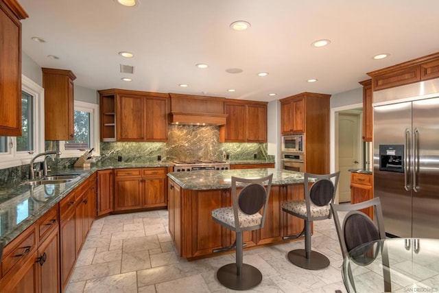 kitchen with sink, a kitchen breakfast bar, a center island, built in appliances, and extractor fan