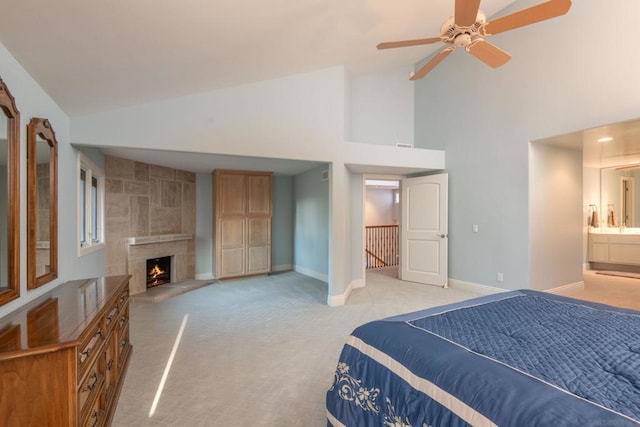 bedroom with connected bathroom, high vaulted ceiling, light carpet, ceiling fan, and a tiled fireplace