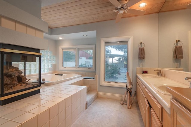 bathroom with wood ceiling, a multi sided fireplace, vanity, a relaxing tiled tub, and ceiling fan