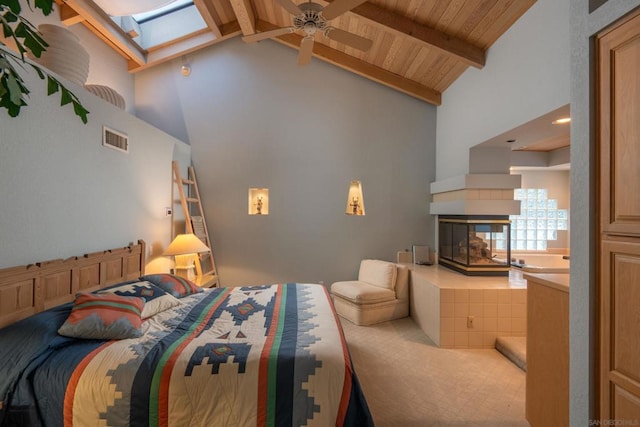 bedroom with a tile fireplace, beam ceiling, a skylight, high vaulted ceiling, and wooden ceiling