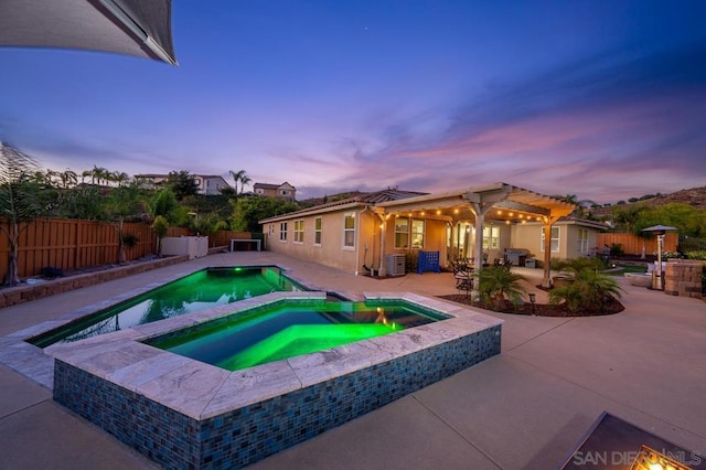 pool at dusk with an in ground hot tub, a pergola, a patio area, and cooling unit