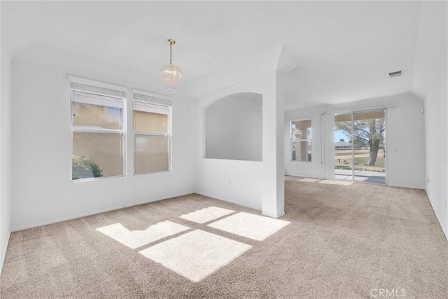 carpeted spare room featuring a chandelier