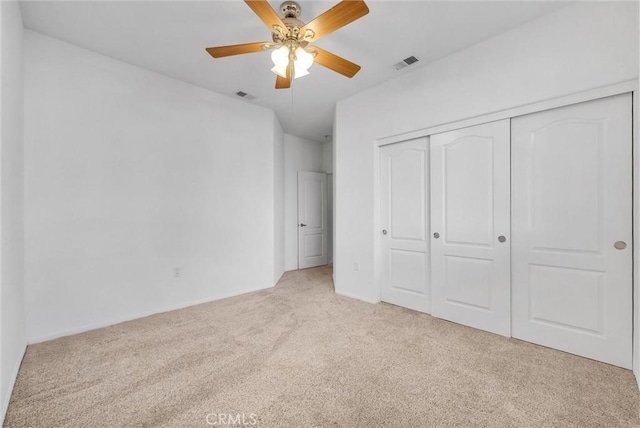 unfurnished bedroom with light carpet, a closet, and ceiling fan