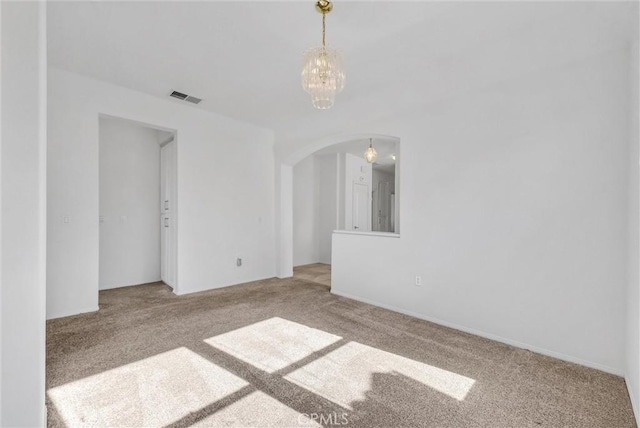 carpeted empty room with an inviting chandelier