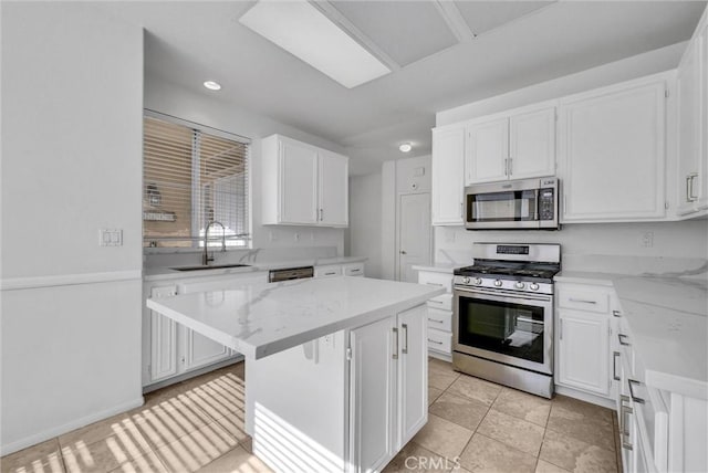 kitchen with appliances with stainless steel finishes, sink, white cabinets, and light stone counters